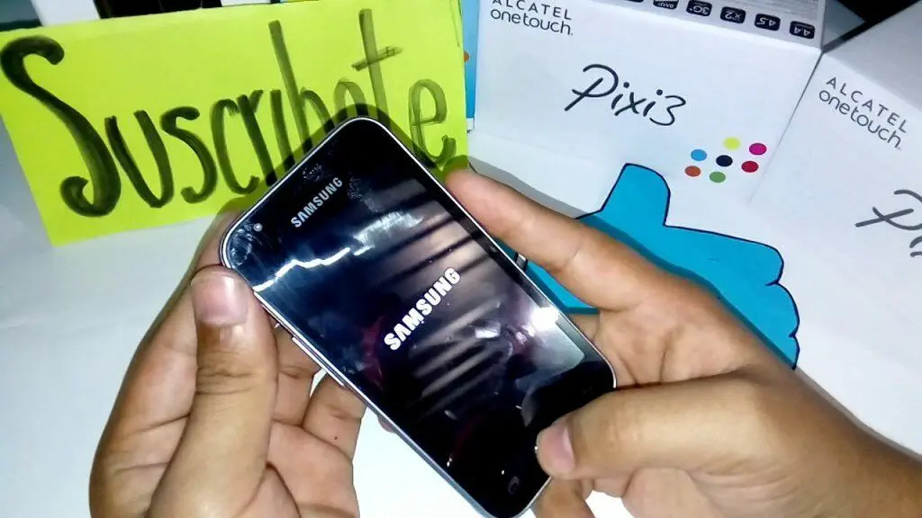 Manos sosteniendo un teléfono Samsung con el logotipo de Samsung. Desbloqueando un Samsung J1.