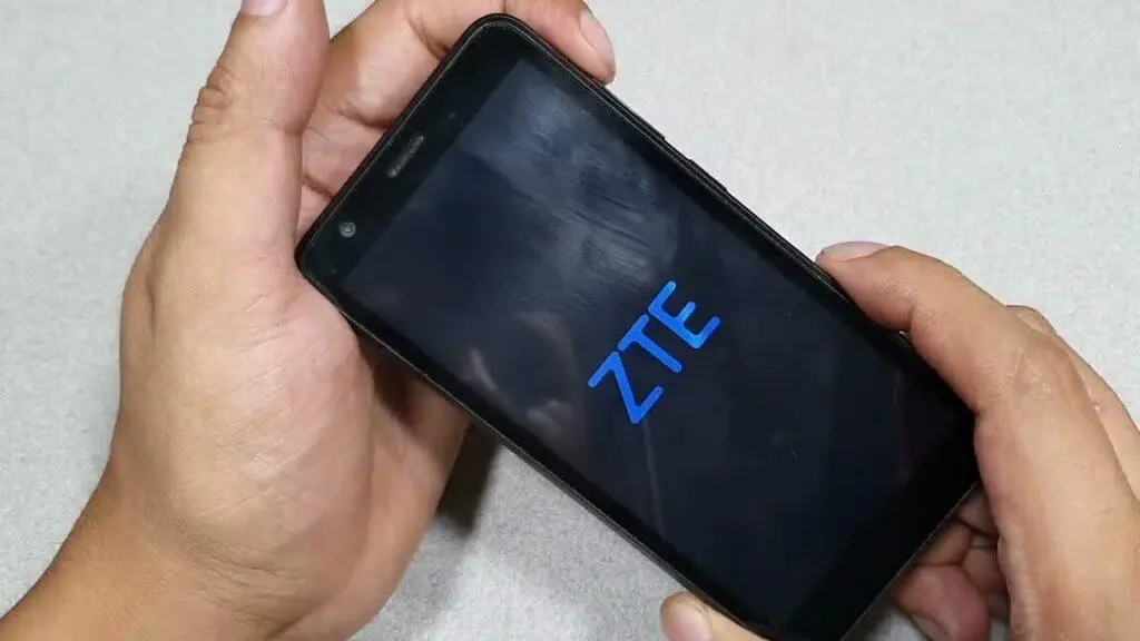 Manos sosteniendo un teléfono ZTE mostrando el logotipo de ZTE en la pantalla.