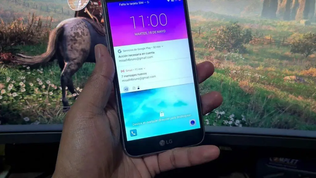 Mano sosteniendo el teléfono LG K10 bloqueado mostrando notificaciones. Desbloqueando el LG K10.
