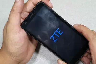 Manos sosteniendo un teléfono ZTE con el logotipo de ZTE en la pantalla. Desbloqueando un teléfono ZTE.